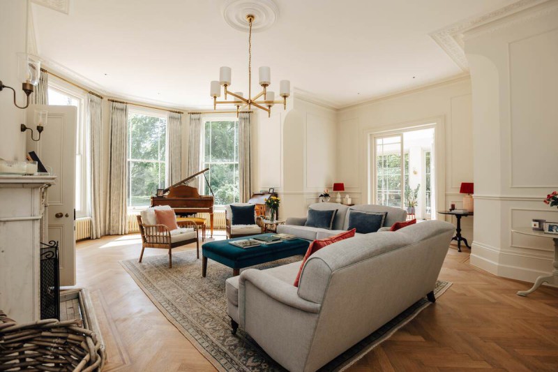 Elegant Victorian living room with bay windows, grand piano, and modern classic décor featuring soft neutral tones and parquet flooring.