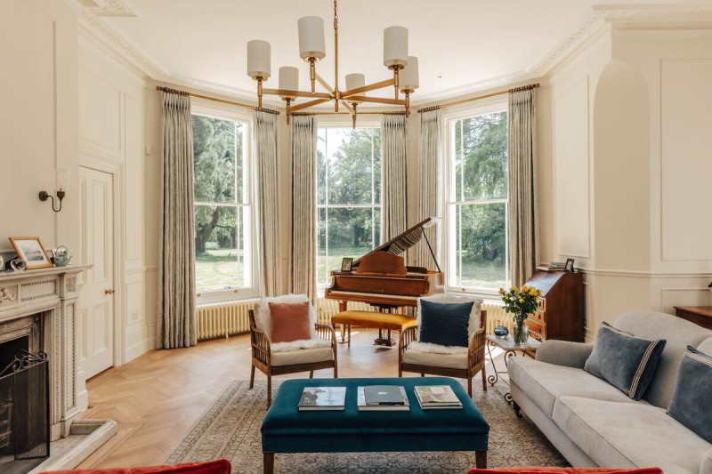 Bright and elegant living room with bay windows, grand piano, and luxury period features in a Georgian-style home.