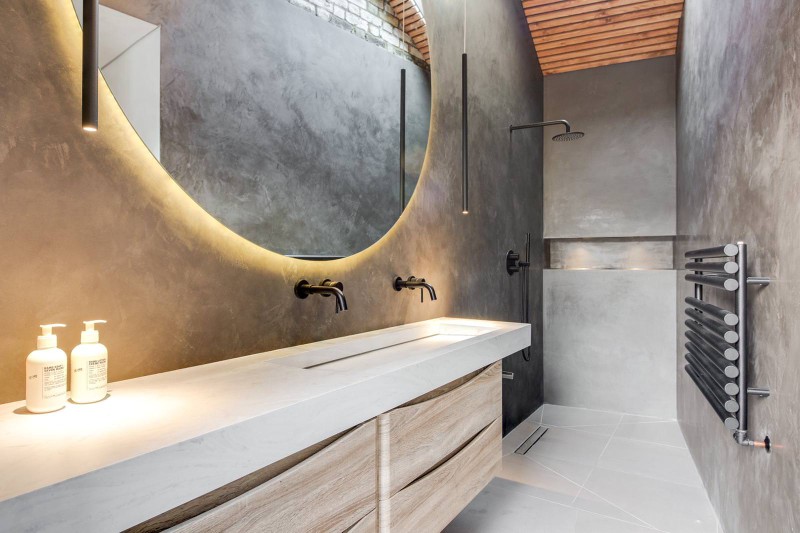 Luxury walk-in shower room with curved mirror, floating vanity, black fittings, and microcement walls