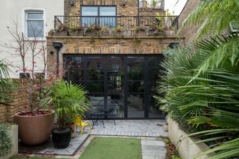 Contemporary London townhouse extension with crittall-style doors, urban courtyard garden, and lush tropical planting