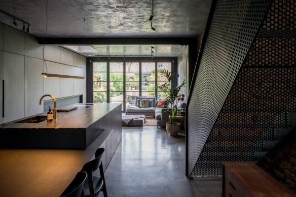 Contemporary open-plan kitchen and living area with industrial finishes, black steel staircase, and garden views
