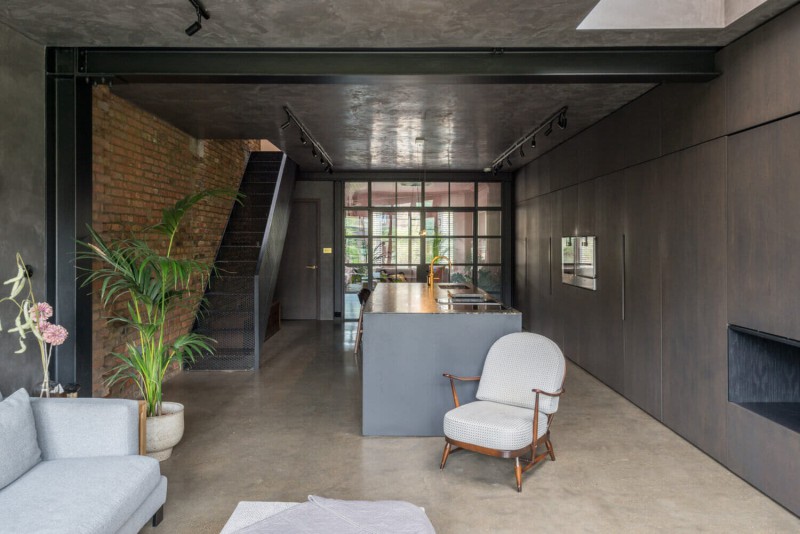 Modern industrial-style kitchen with exposed brick wall, sleek cabinetry, and central island with gold tap