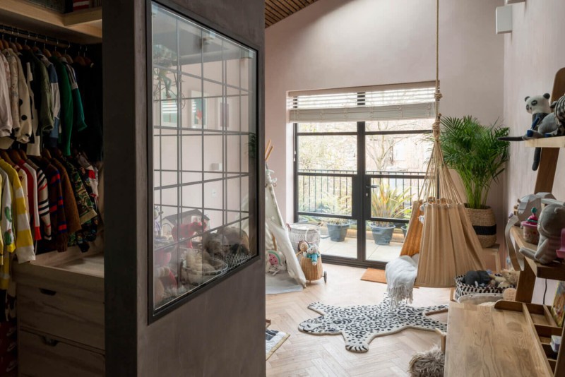 Scandi-style kids’ room with skylight, hanging hammock chair, wooden ceiling, and playful animal rug