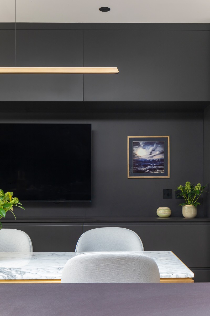 Contemporary dining space with marble table, soft grey chairs, matte black cabinetry, and wall-mounted TV
