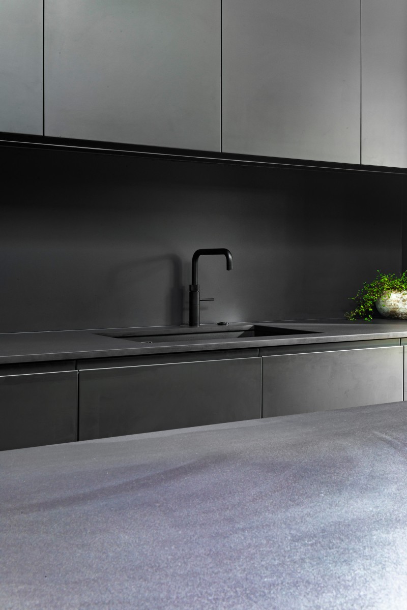 Minimalist matte black kitchen with integrated sink, flat-panel cabinetry, and monochrome worktop