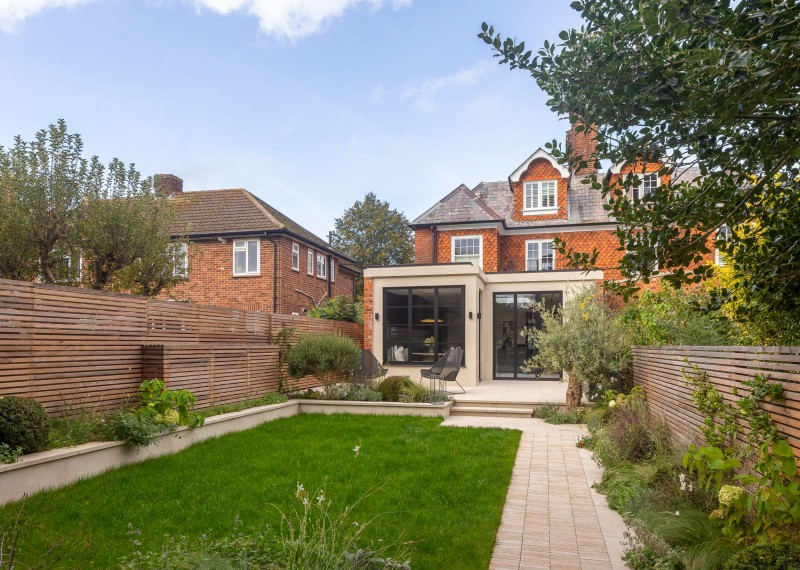 Modern rear extension with black-framed glazing, private landscaped garden, and seamless indoor-outdoor flow.