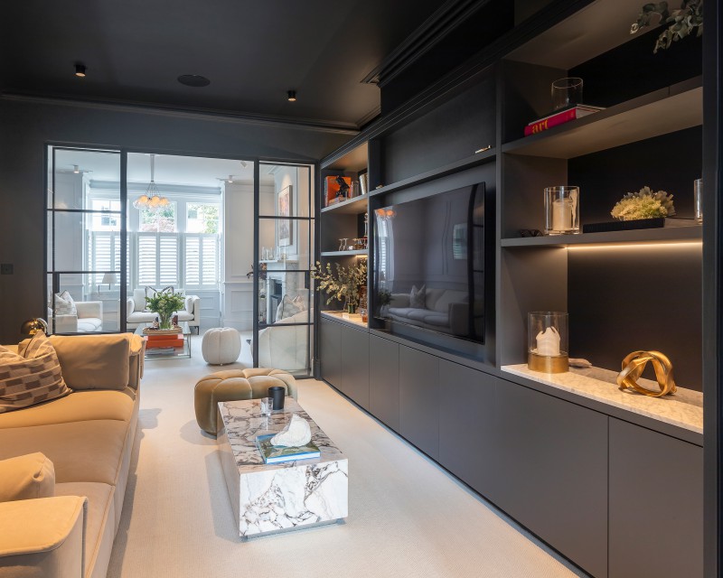Luxury living room with dark feature joinery, marble coffee table, and crittall-style doors leading to bright, elegant sitting area