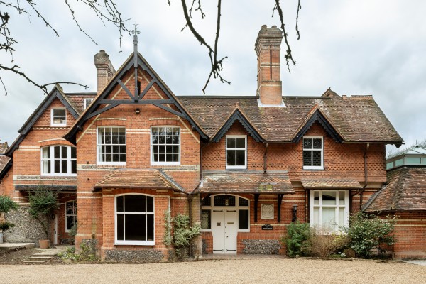 Striking red brick Victorian house with ornate gables, tall chimneys, and period sash windows, set on a gravel driveway