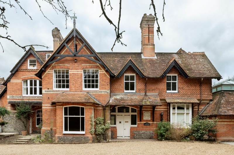 Striking red brick Victorian house with ornate gables, tall chimneys, and period sash windows, set on a gravel driveway